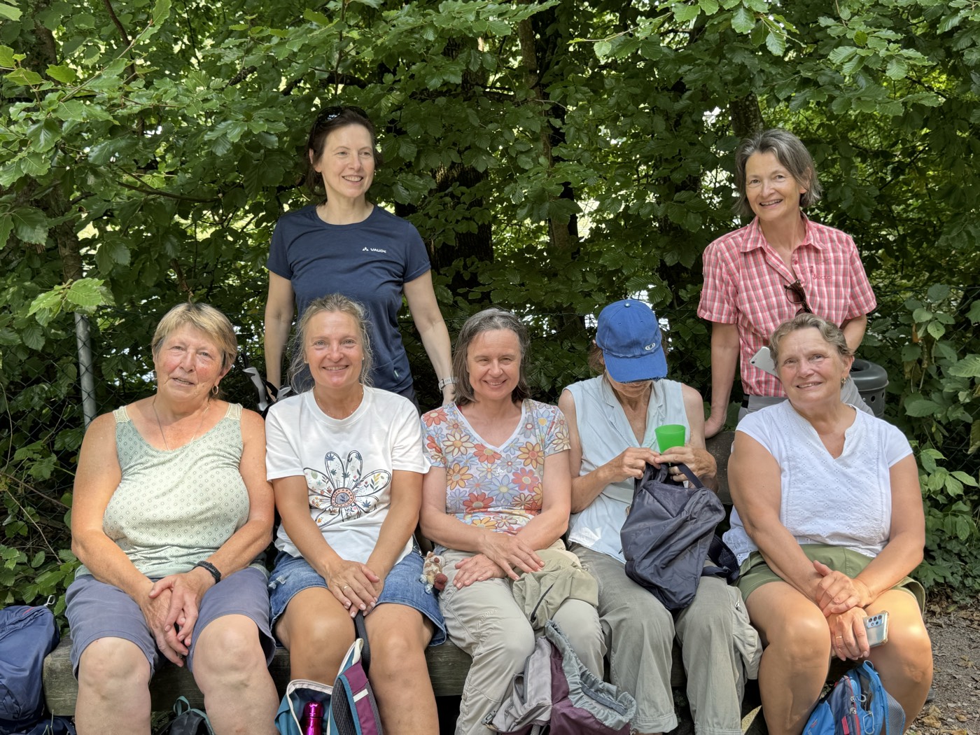 Eine kleine Gruppe Frauen lachend auf einer Bank im Wald